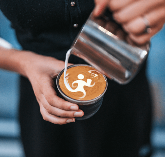 Barista pouring Responsible Cafes logo into coffee foam
